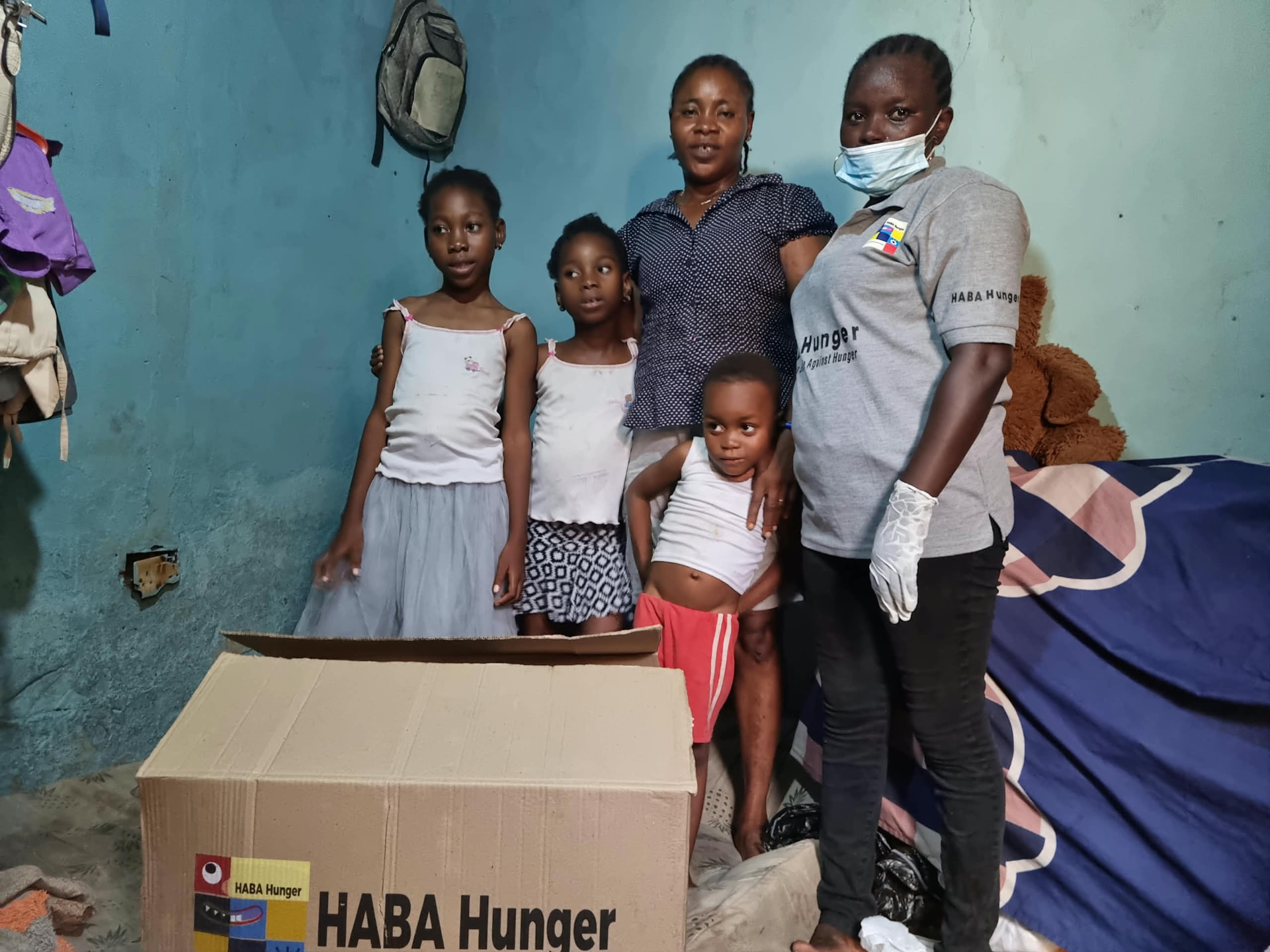 A HABA Hunger volunteer with a mother and her children beside their food support box